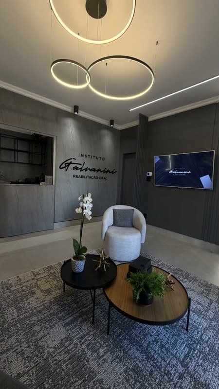 Recepção de clínica com luminárias circulares e poltrona clara